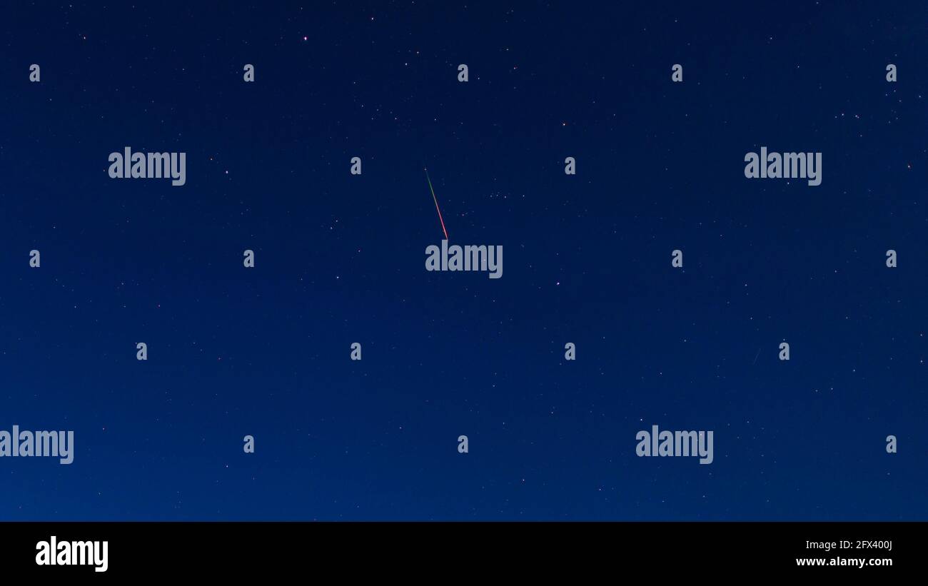Bright red-green meteor of Perseid flow in the night sky Stock Photo
