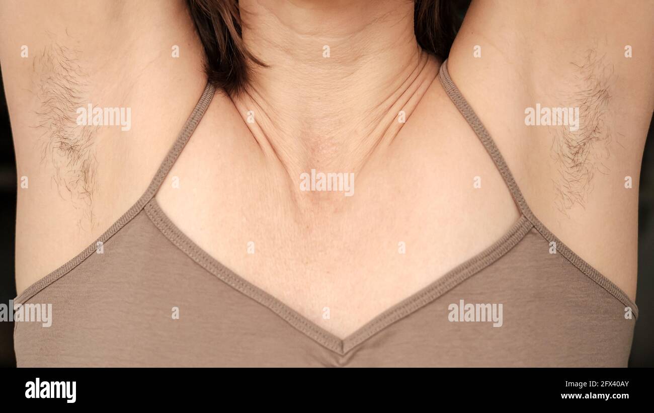 Hairy, unshaven female armpits and raised arms up. Concept of body positive and the adoption of its naturalness.  Stock Photo