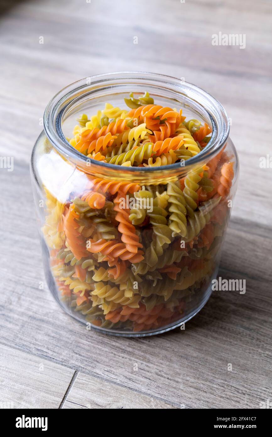 A portrait of a glass pot, jar or bowl full of spirelli in three different  colors. The uncooked tricolore italian pasta variant is orange, yellow and  Stock Photo - Alamy