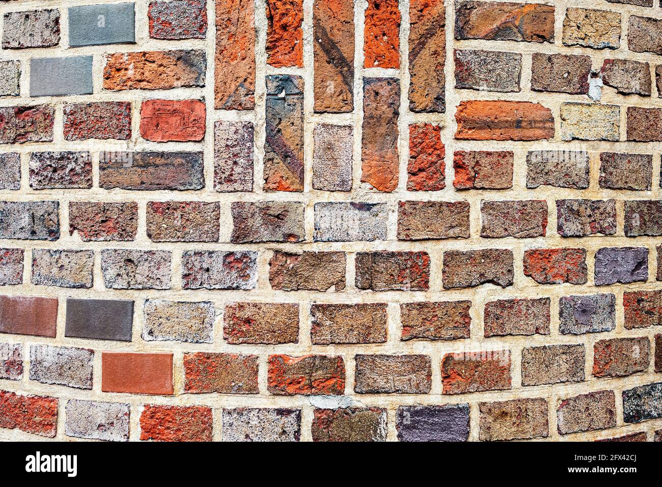 Old masonry of multicolored bricks in different shades of red and black Stock Photo