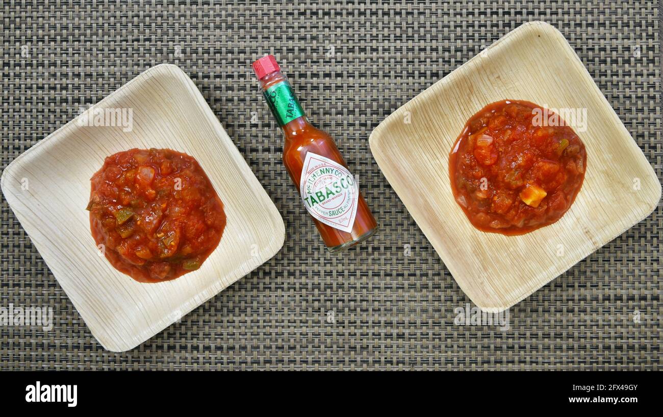 2 identical bowls with freshly made salsa with a bottle of tabasco sauce Stock Photo
