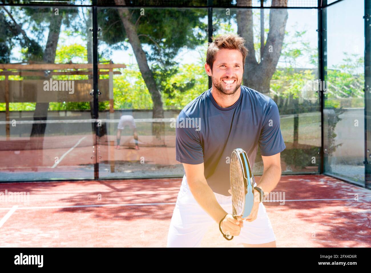 young guy plays padel tennis outdoor summer sport court getting fit Stock Photo