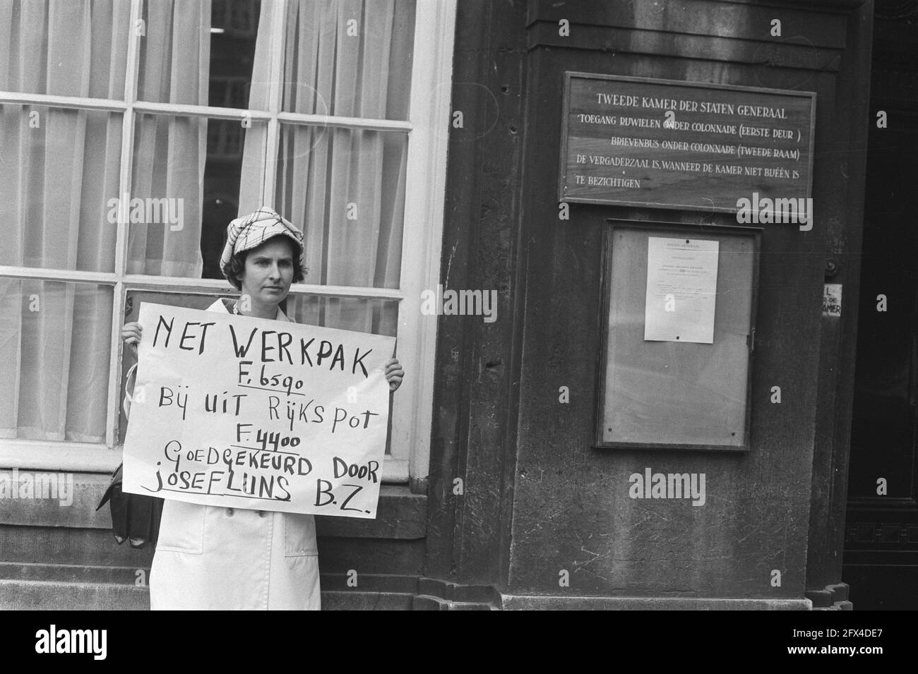Demonstrator at Binnenhof holding sign reading Net work suit F. 6590. At out Reich spot F. 4400. Approved by Josef Luns B.Z. Foreign Affairs], May 25, 1971, demonstrations, signs, squares, The Netherlands, 20th century press agency photo, news to remember, documentary, historic photography 1945-1990, visual stories, human history of the Twentieth Century, capturing moments in time Stock Photo