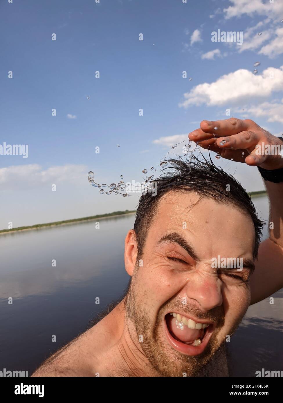 Happy man splashing and pouring fresh water on his head to refresh