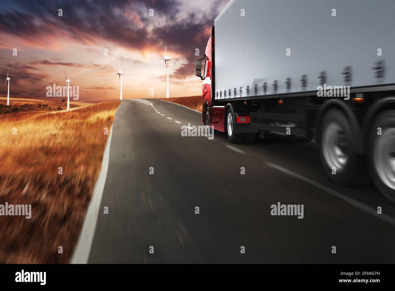 Red modern truck moving fast on the road at sunset Stock Photo
