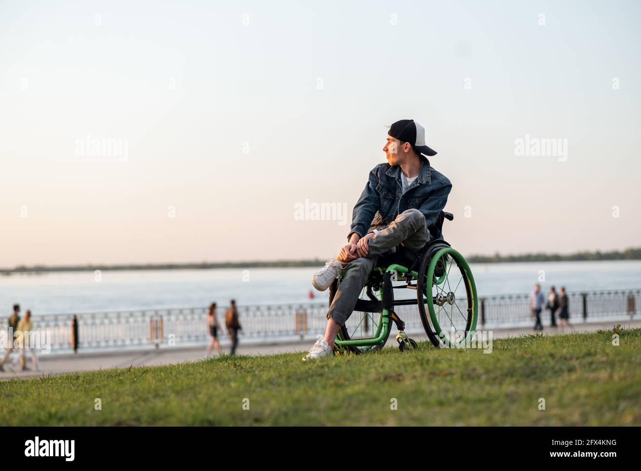 a young man in a wheelchair, walking around the city, enjoying the sunset Stock Photo