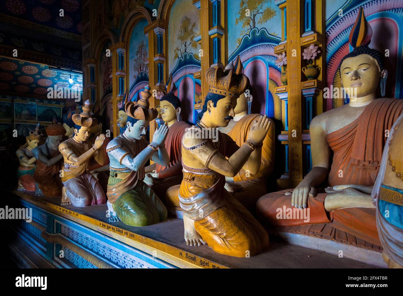 Dikwella, Wewurukannala Vihara Temple, Sri Lanka: interior room with seated Buddhas worshiped by kneeling statues Stock Photo