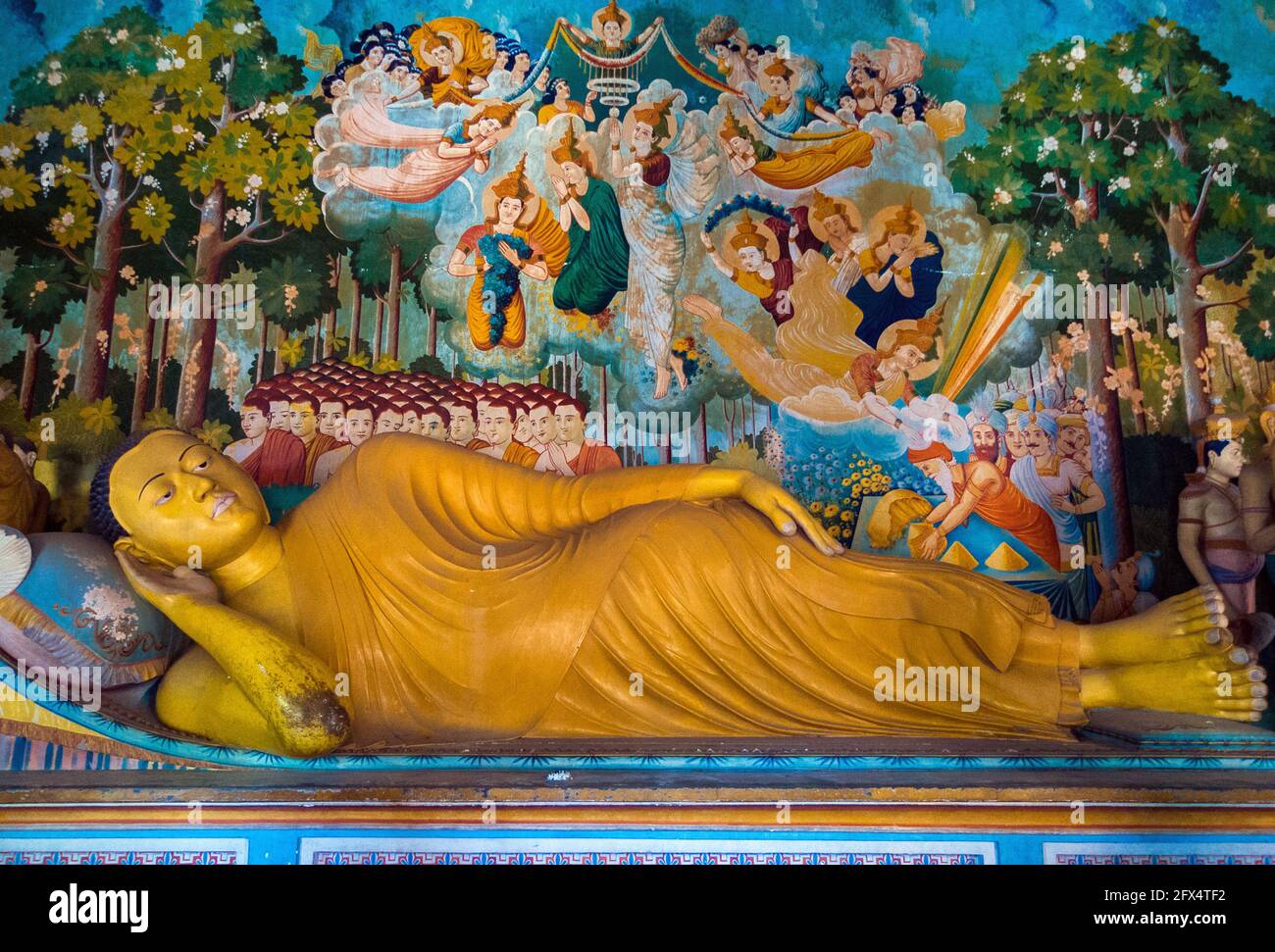 Dikwella, Wewurukannala Vihara Temple, Sri Lanka: interior room with statue of reclining Buddha with a fresco behind Stock Photo