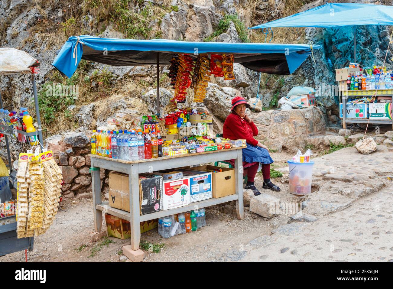 Elderly female stallholder and snack stall at Chinchero, a small Andean rustic village in the Sacred Valley, Urubamba Province, Cusco Region, Peru Stock Photo