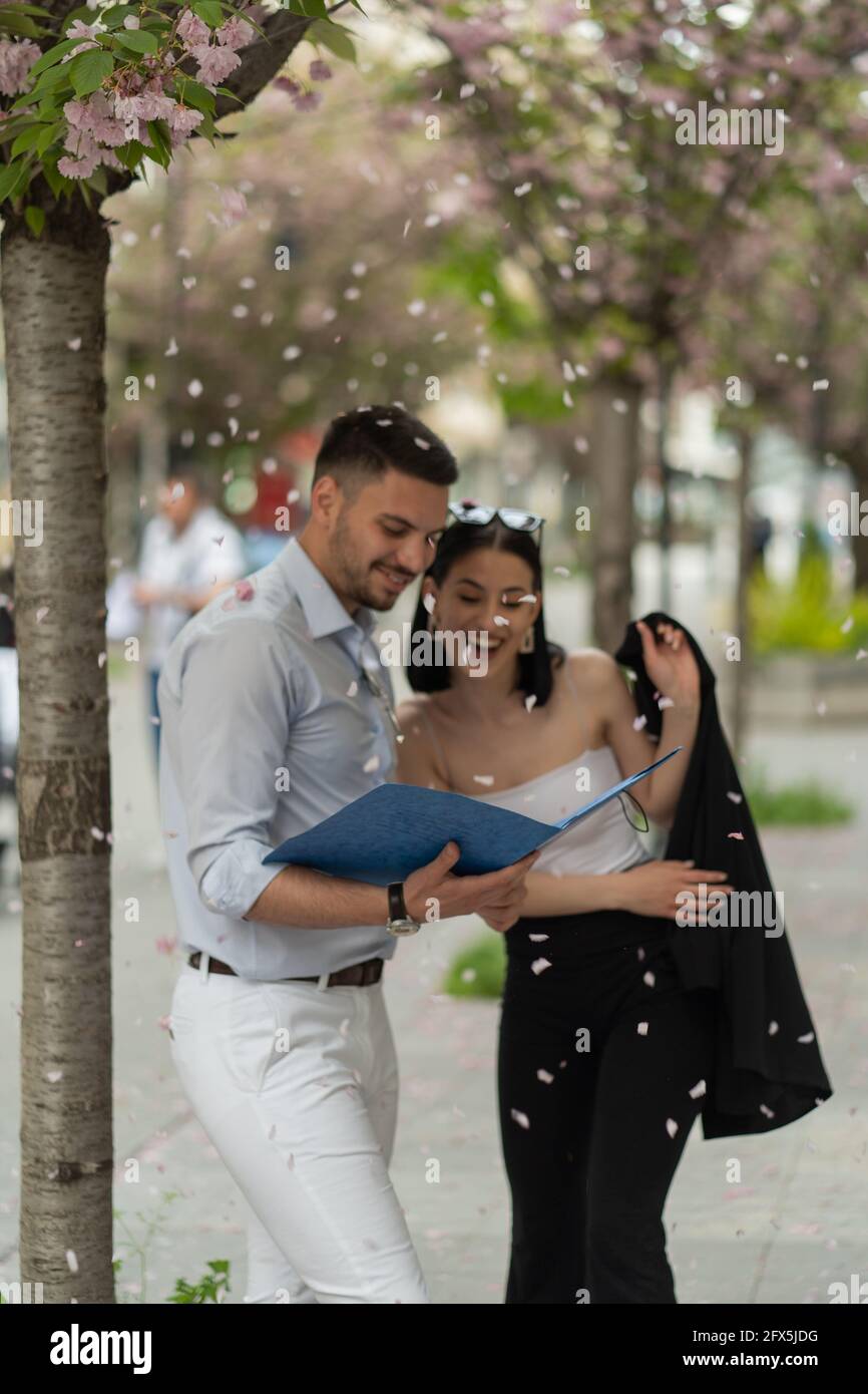 Two business people laughinf under the falling flower leafs, selective focus Stock Photo