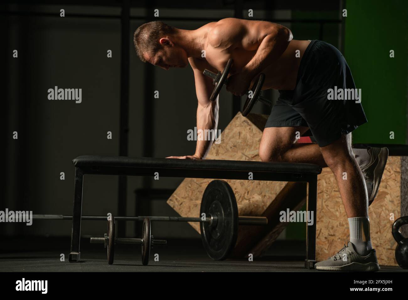 Good looking young man doing triceps dumbbell kickback exercises with