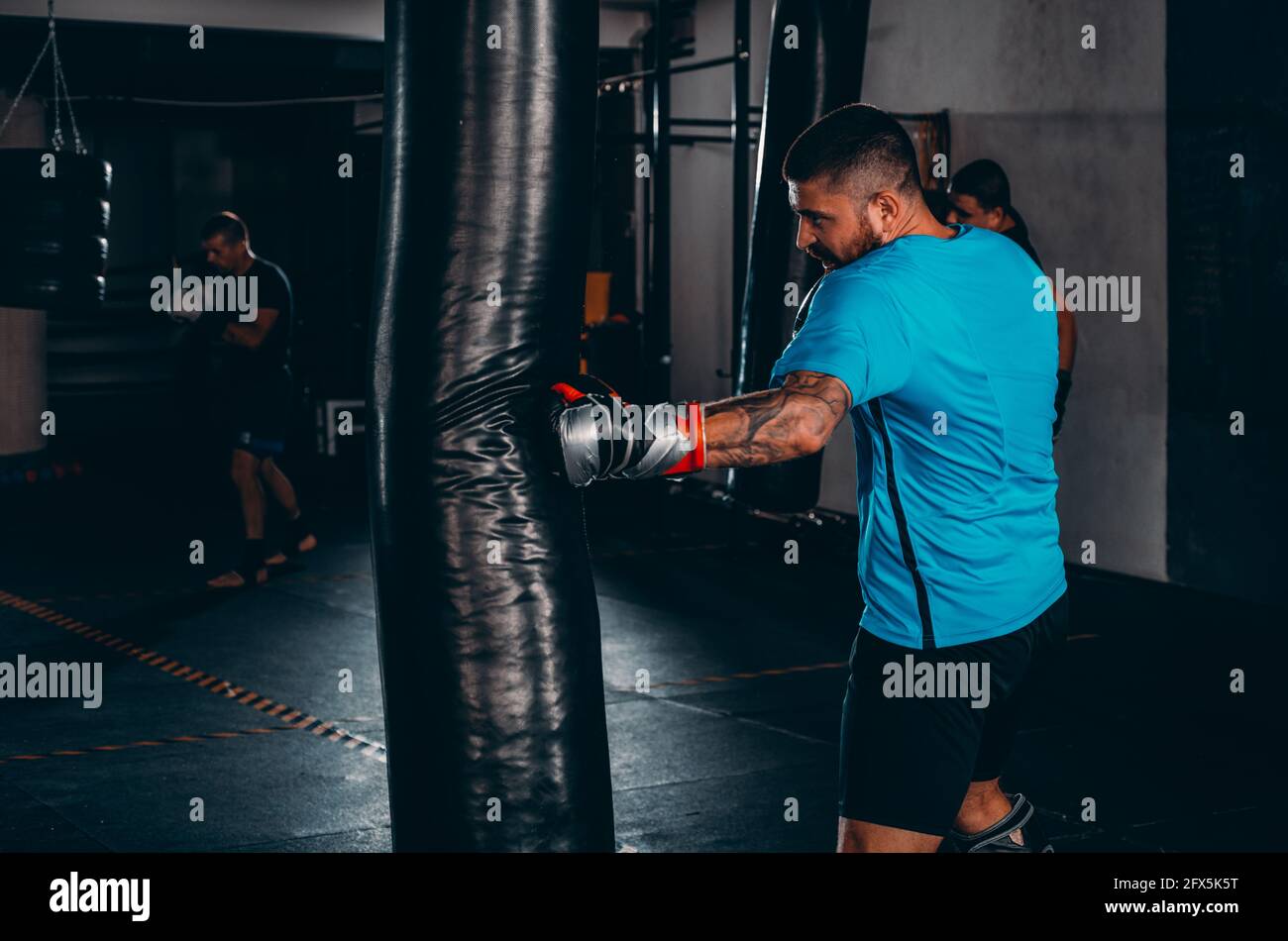 Boxer man during boxing hitting heavy bag at training fitness gym Stock