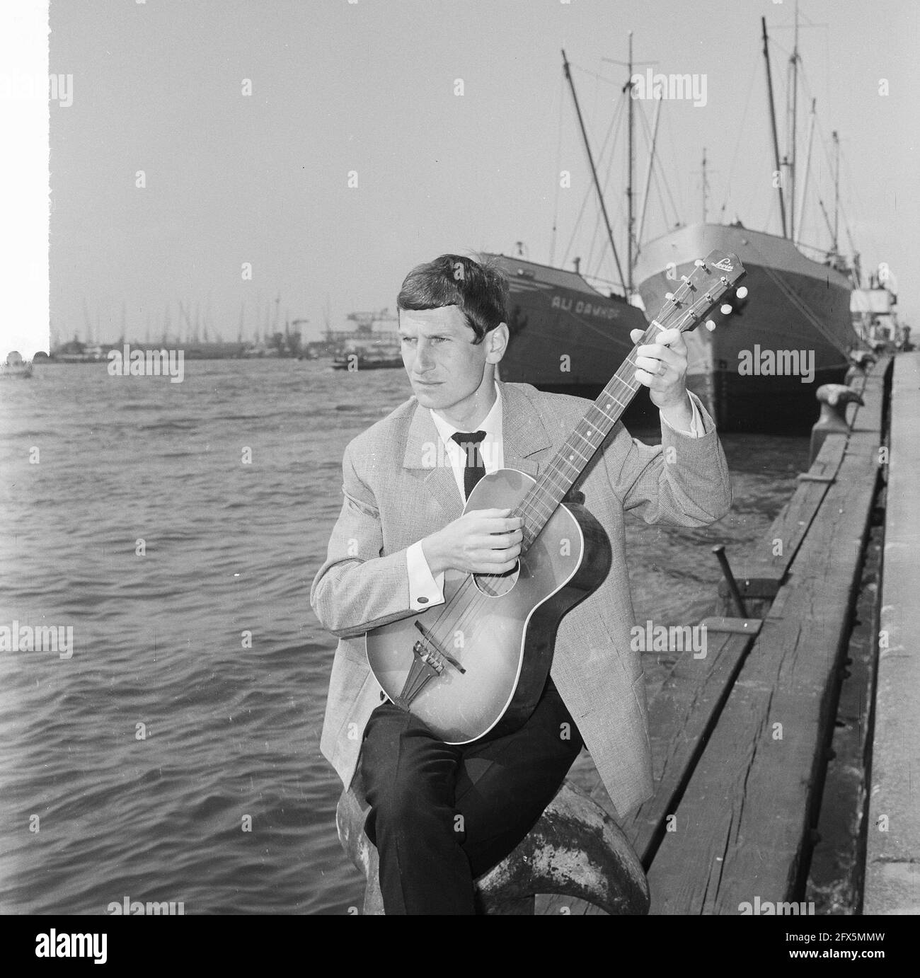 Gerard Cox in TV show of NCRV, singer Dutch chanson here at the port of Rotterdam, May 20, 1964, TV shows, guitars, ports, singers, The Netherlands, 20th century press agency photo, news to remember, documentary, historic photography 1945-1990, visual stories, human history of the Twentieth Century, capturing moments in time Stock Photo