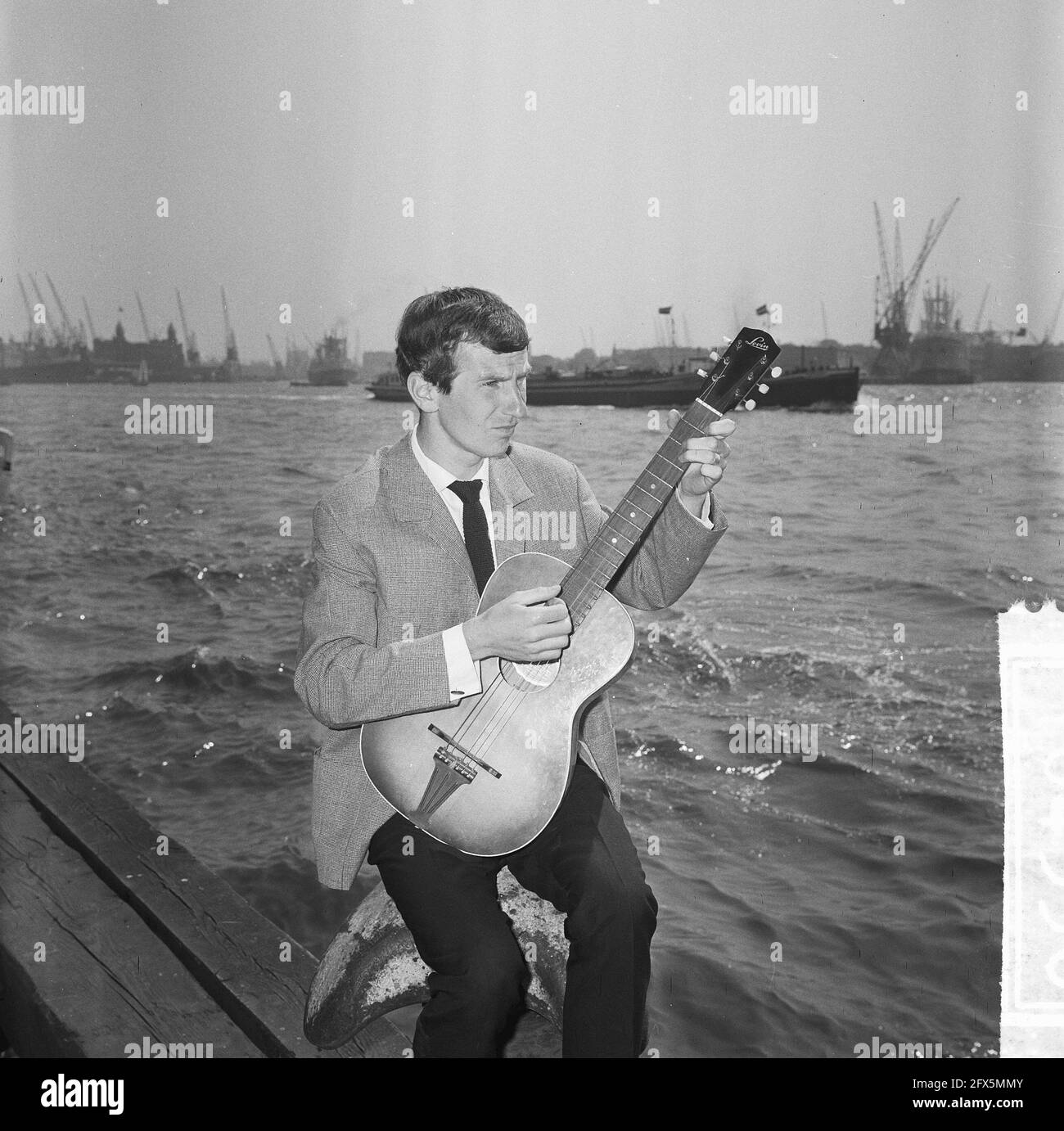 Gerard Cox in TV show of NCRV, singer Dutch chanson here at the port of Rotterdam, May 20, 1964, TV shows, guitars, ports, singers, The Netherlands, 20th century press agency photo, news to remember, documentary, historic photography 1945-1990, visual stories, human history of the Twentieth Century, capturing moments in time Stock Photo
