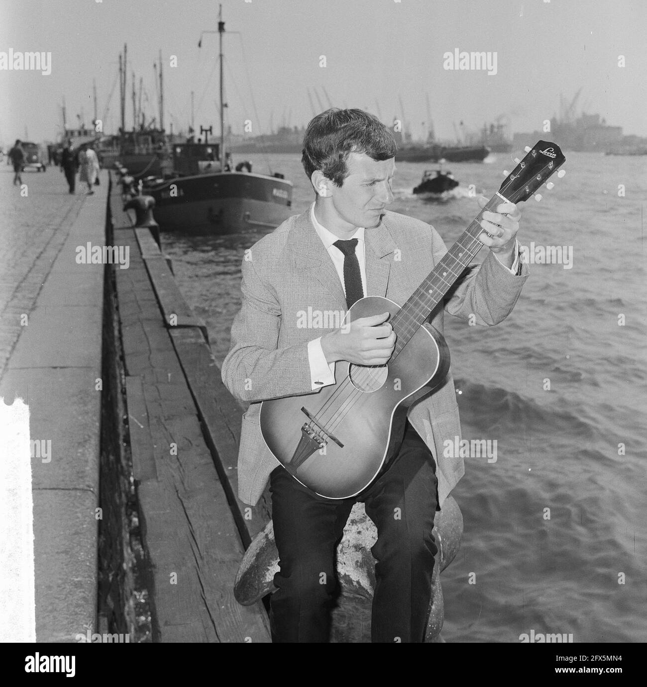 Gerard Cox in TV show of NCRV, singer Dutch chanson here at the port of Rotterdam, May 20, 1964, TV shows, guitars, ports, singers, The Netherlands, 20th century press agency photo, news to remember, documentary, historic photography 1945-1990, visual stories, human history of the Twentieth Century, capturing moments in time Stock Photo