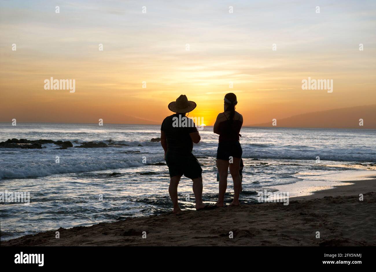 Couple watching the sunset from a beach in Tamarindo, Costa Rica, Central America Stock Photo