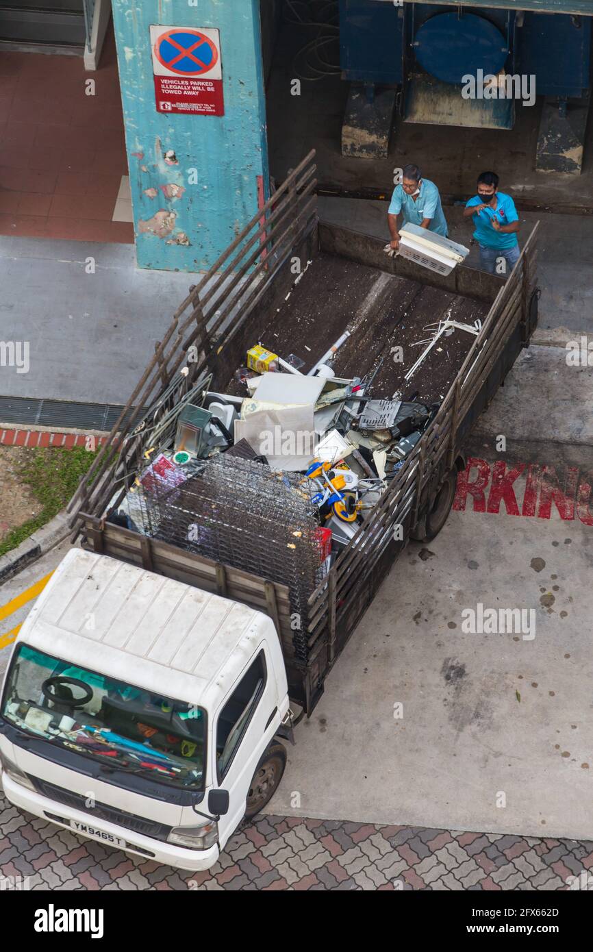 Aerial view of 2 Indian workers are throwing unwanted household plastic items from the rubbish chute area onto the truck. Singapore Stock Photo
