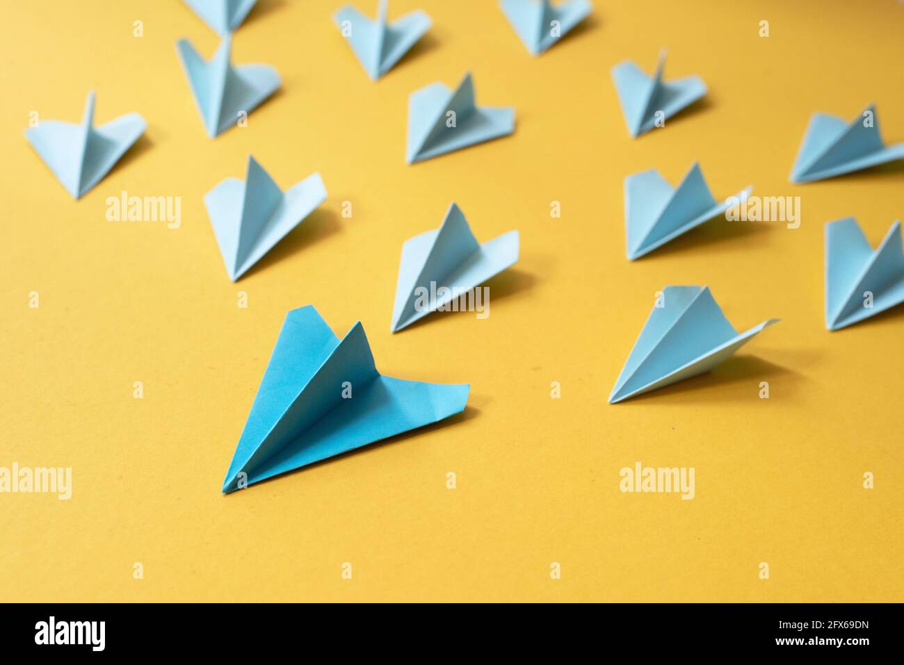Group of blue paper aeroplane origami on yellow background. Concept of leadership, teamwork and