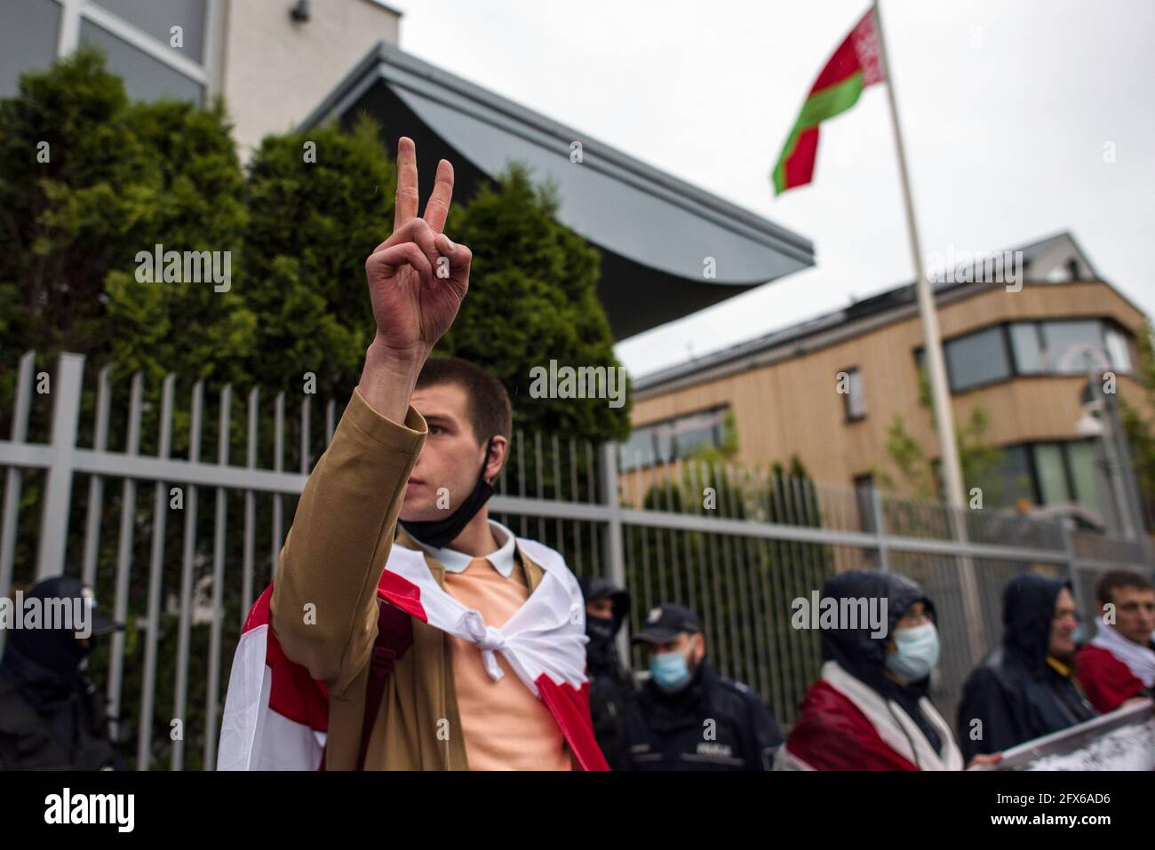 Warsaw, Poland. 25th May, 2021. A protester wrapped in the forbidden flag holds up his hand in a gesture of victory during the protest.Belarusians residents in Poland gathered outside the Embassy of Belarus to protest against the arrest of Roman Protesevich, dissident journalist and the repressions on activists by Aleksander Lukashenko. (Photo by Attila Husejnow/SOPA Images/Sipa USA) Credit: Sipa USA/Alamy Live News Stock Photo