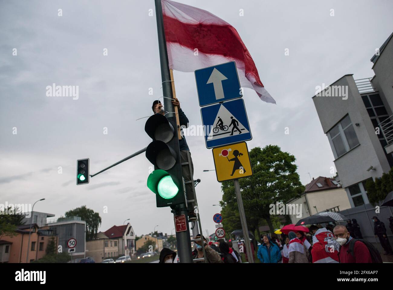 Warsaw, Poland. 25th May, 2021. A protester hangs the forbidden historical Belarusian flag on a pole with traffic lights during the protest.Belarusians residents in Poland gathered outside the Embassy of Belarus to protest against the arrest of Roman Protesevich, dissident journalist and the repressions on activists by Aleksander Lukashenko. (Photo by Attila Husejnow/SOPA Images/Sipa USA) Credit: Sipa USA/Alamy Live News Stock Photo