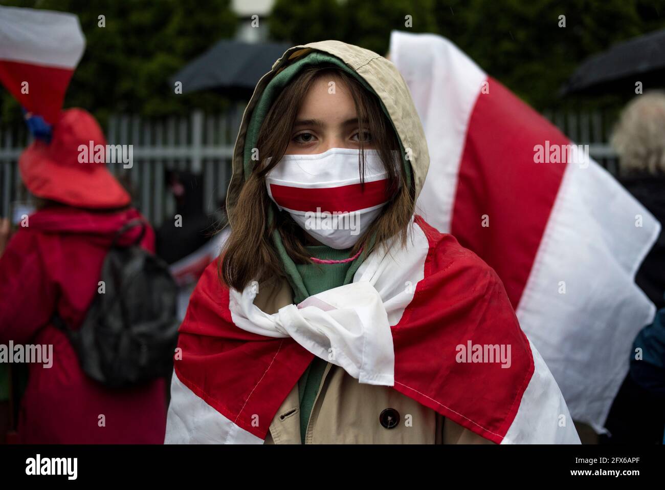 Warsaw, Poland. 25th May, 2021. A young protester wears a face mask in the colors of the forbidden historical Belarusian flag during the protest.Belarusians residents in Poland gathered outside the Embassy of Belarus to protest against the arrest of Roman Protesevich, dissident journalist and the repressions on activists by Aleksander Lukashenko. (Photo by Attila Husejnow/SOPA Images/Sipa USA) Credit: Sipa USA/Alamy Live News Stock Photo