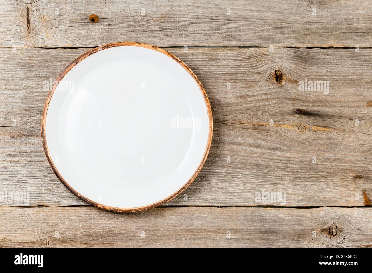 Empty white ceramic dish on rustic wooden table Stock Photo
