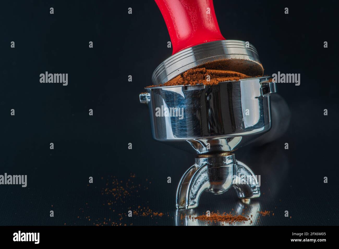 Barista accessories, portafilter with fresh ground coffee and tamper on shiny table bar Stock Photo