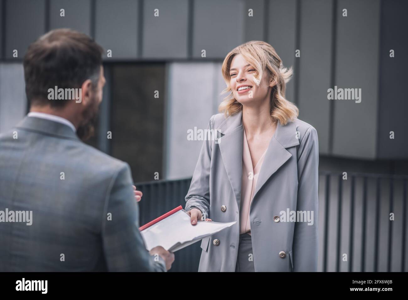 Man handing over documents to smiling business woman Stock Photo