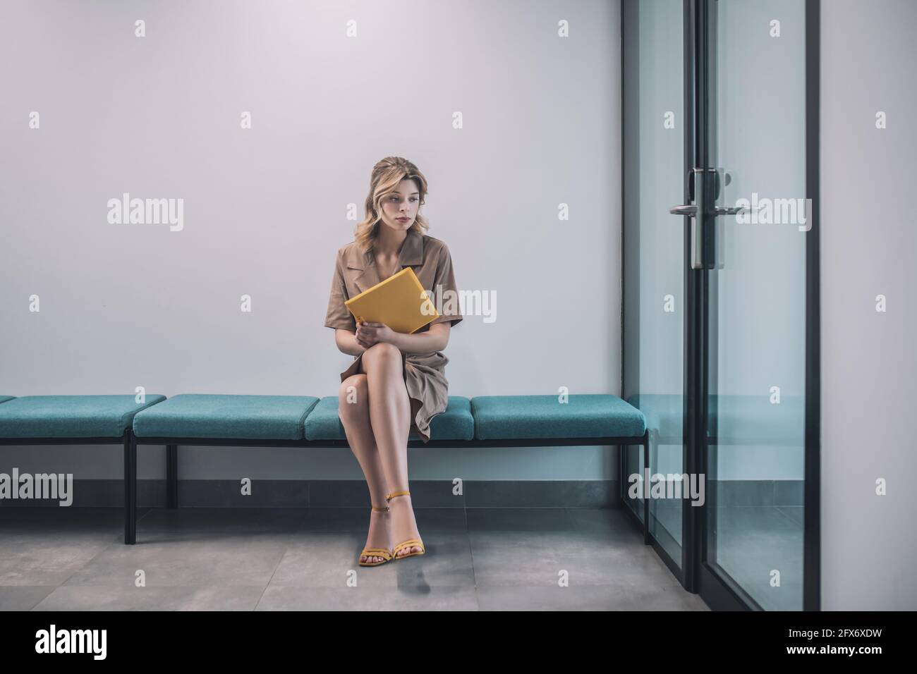Sad woman with documents sitting in office corridor Stock Photo