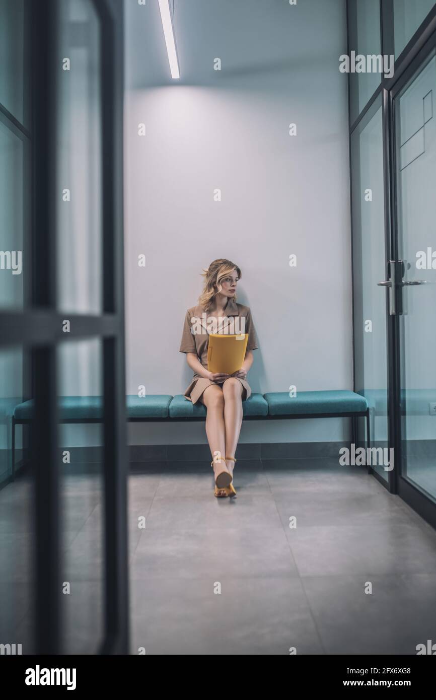 Young blonde woman waiting in the office corridor Stock Photo