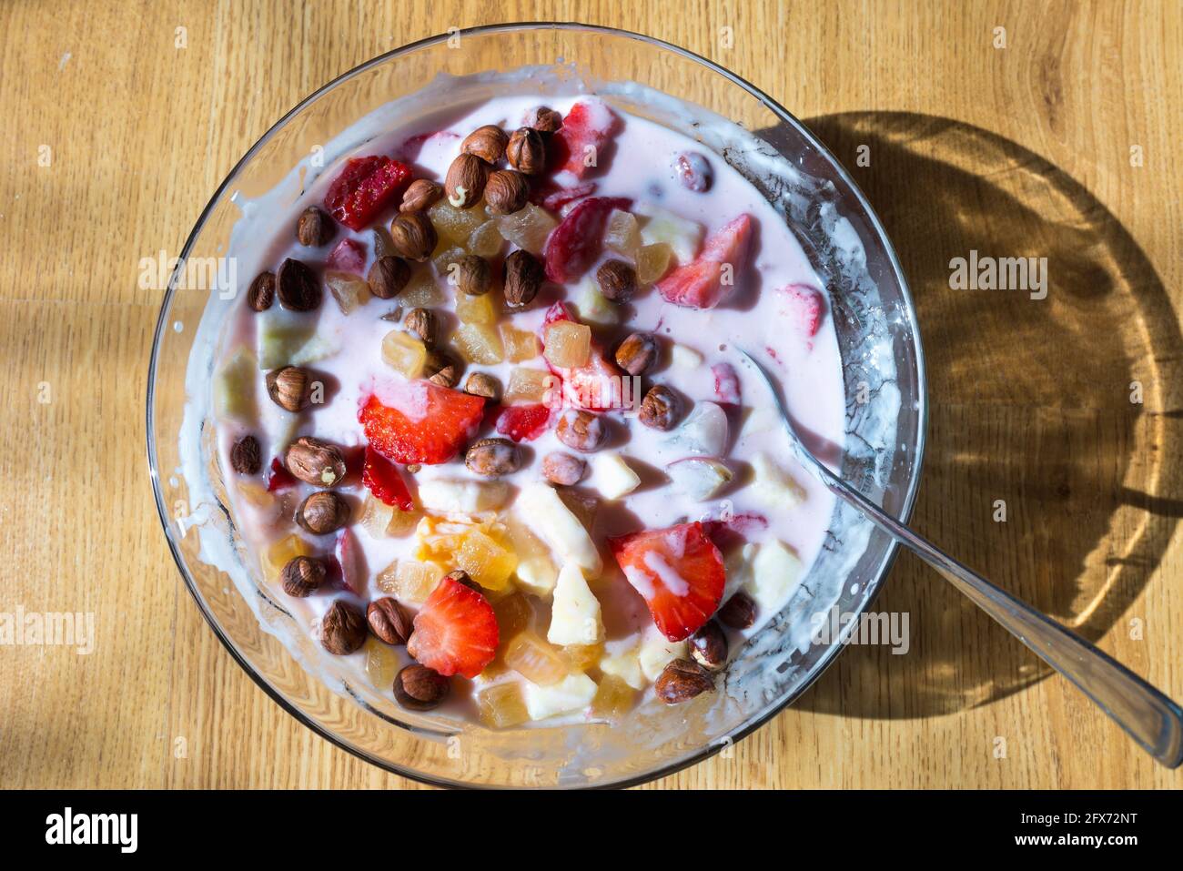 Healthy breakfast yogurt bowl,banana,hazelnuts, strawberries,oranges,apple dried fruit on a table top view. Clean eating, detox, allergy friendly conc Stock Photo