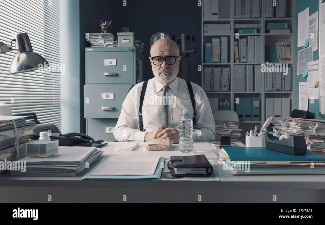 Corporate businessman having a sad desk lunch alone in the office Stock Photo