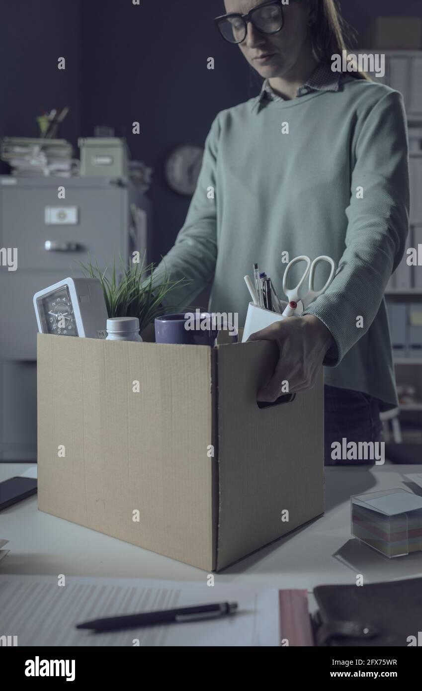 Sad woman packing her belongings in the office after being fired Stock Photo