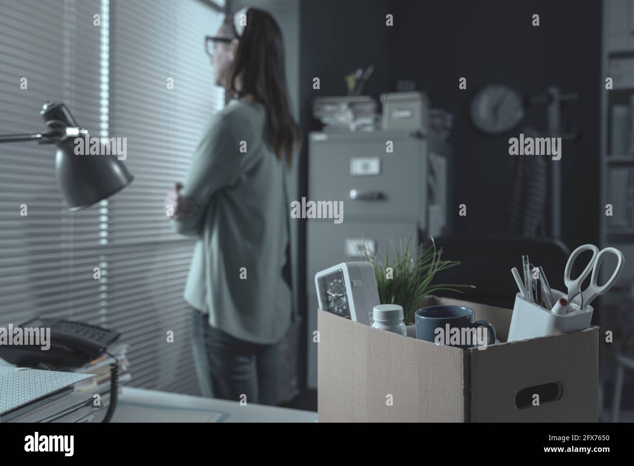 Pensive woman in the office packing her belongings, she has been fired Stock Photo