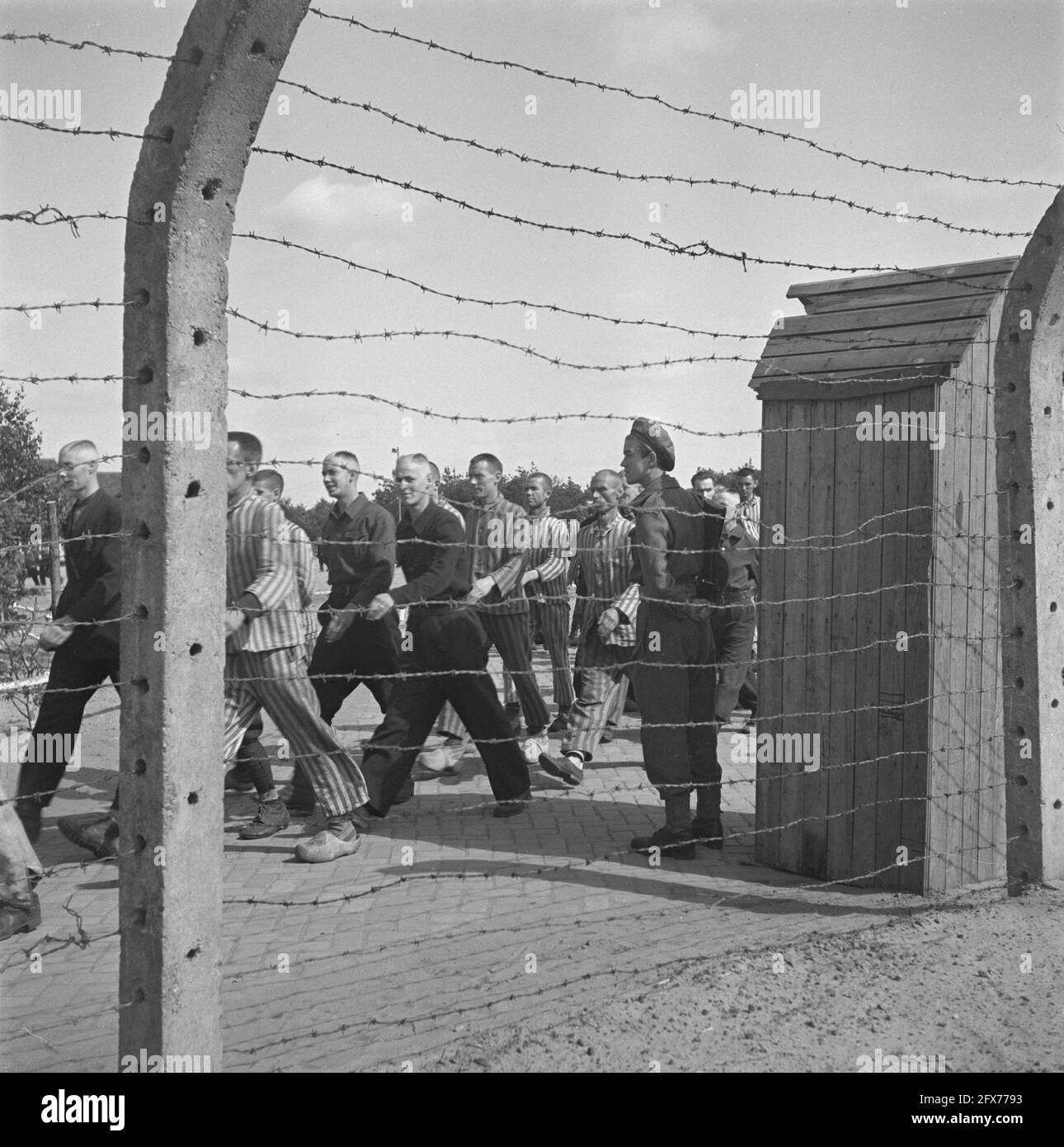 In the penal camp at Vught, 7000 Dutch collaborators and traitors are locked up. Soldiers of the Dutch Stoottroepen are in charge of the security, especially of the 300 Dutch SS men. Led by the camp commander, Major L. Mennes, and his aides, these prisoners are used to clear the area around Vught of land mines, among other things. They were dressed in the blue and white striped prisoner's uniforms of the former Dutchmen captured by the Germans. The prisoners receive the minimum civilian ration, which is also reduced because all delicacies have been taken off. While waiting for their final Stock Photo