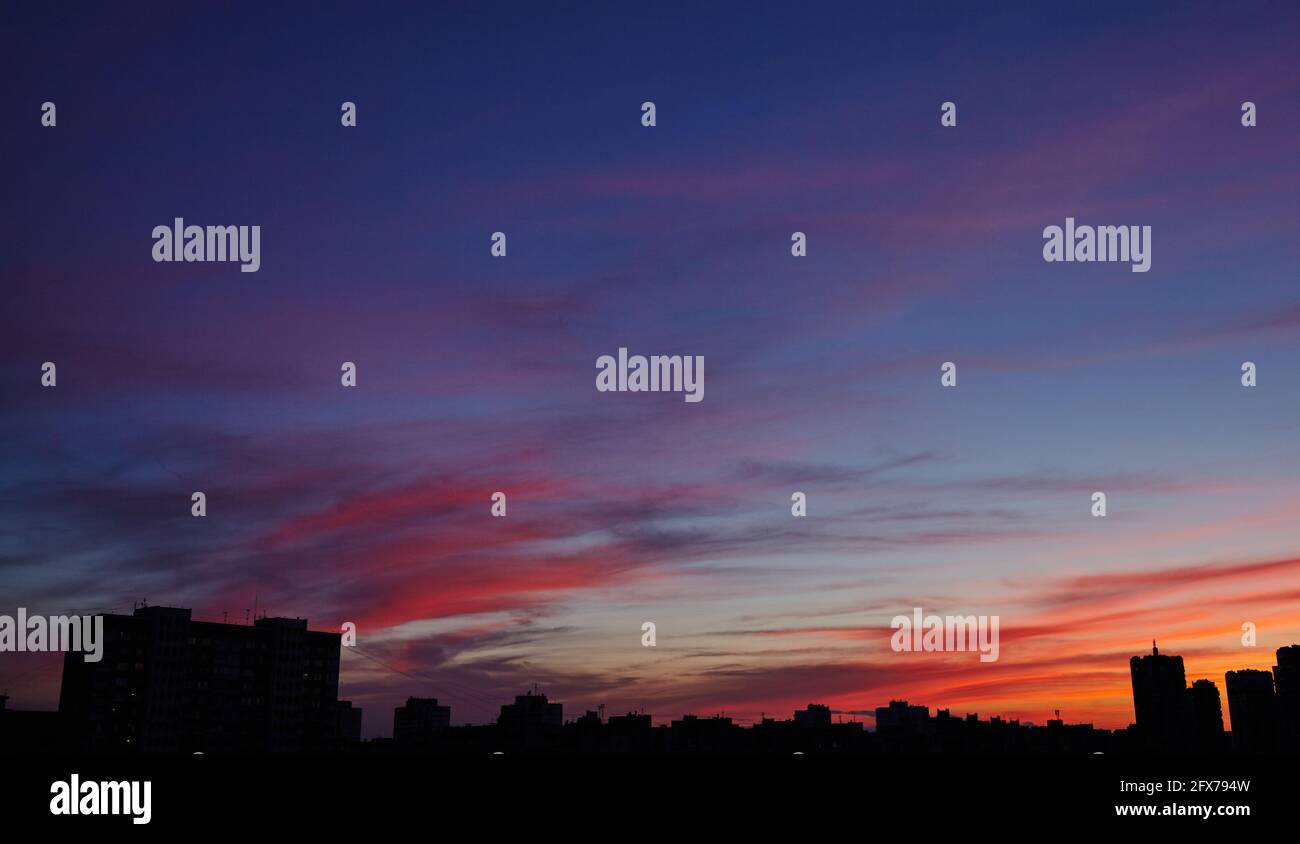 Colorful dramatic sky with clouds at sunset. City during warm sunset ...
