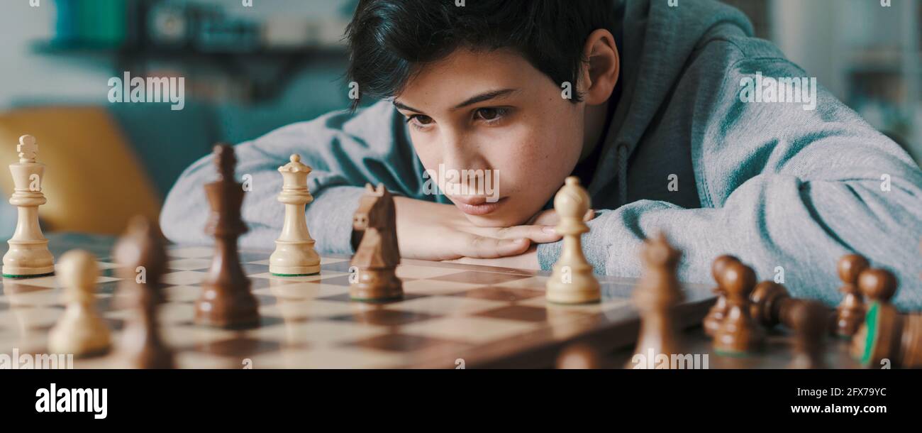 Concentrated serious boy developing chess gambit, strategy ,playing board  game to winner clever concentration and thinking child while playing chess.  Learning, tactics and analysis concept. Free Photo