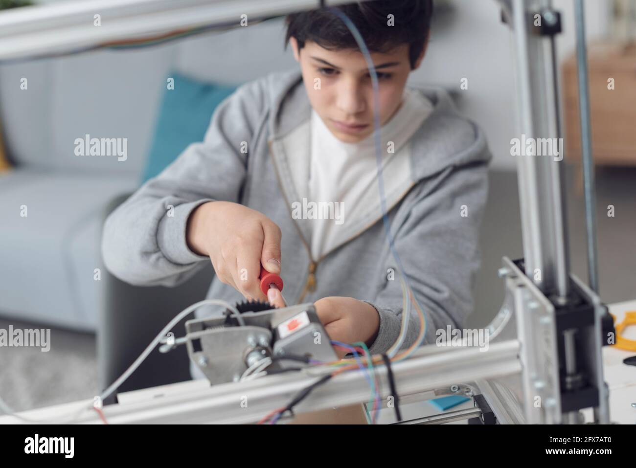 Smart young boy learning how to use a 3D printer at home, science and technology concept Stock Photo
