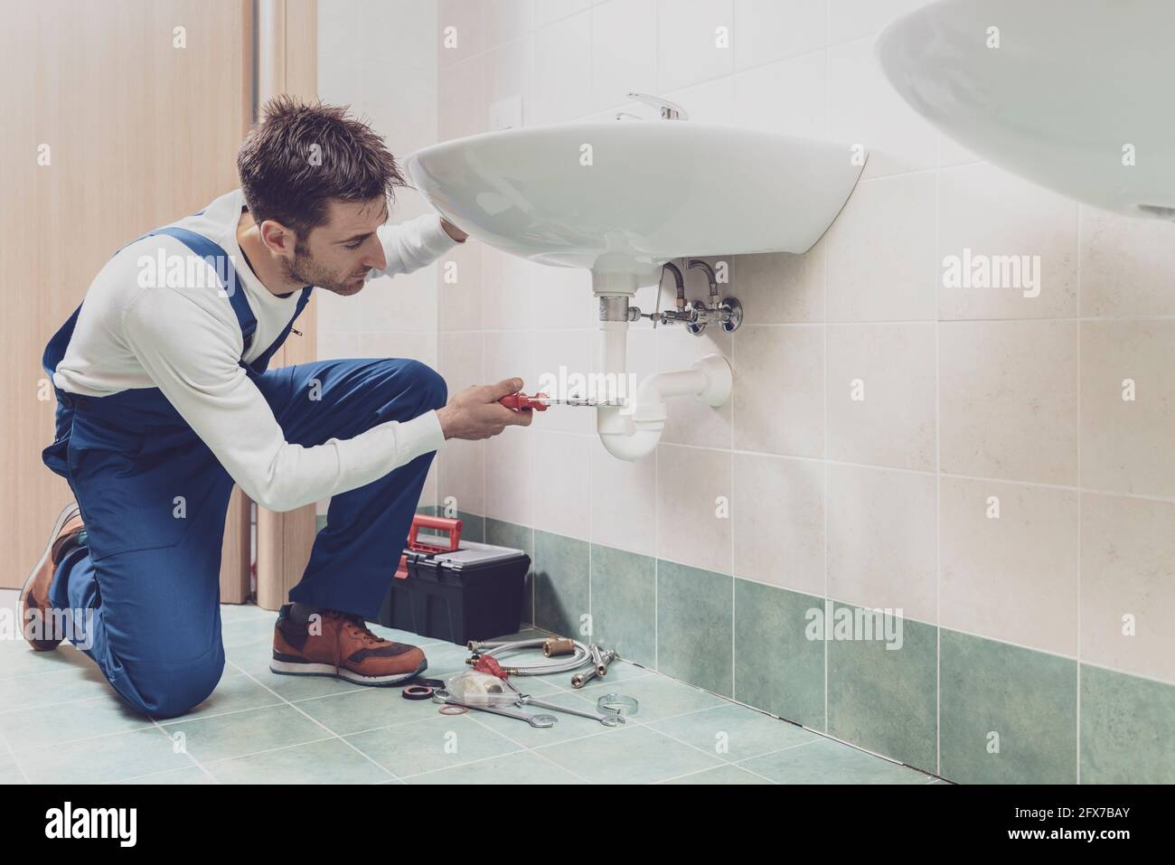 Professional plumber installing or fixing a sink at home Stock Photo