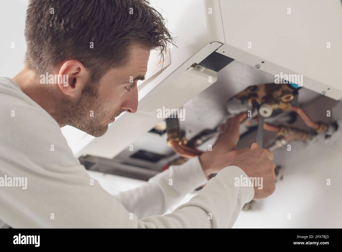 Professional plumber checking a boiler and pipes, he is using a wrench Stock Photo