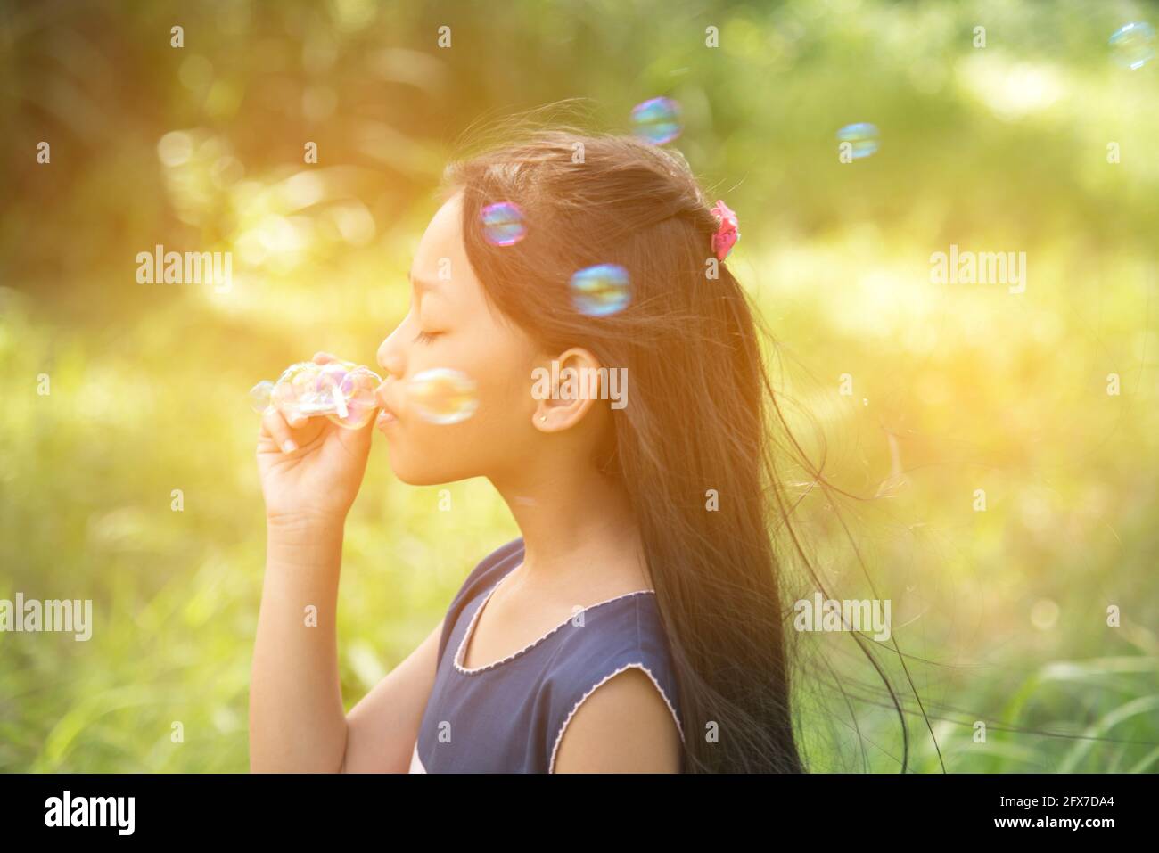 Cute girl play blowing bubble on playground with hard sun light. Little ...