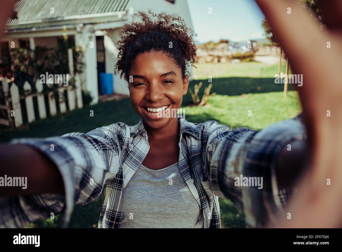 Mixed race female taking selfie with cellular device standing outdoors on farm  Stock Photo