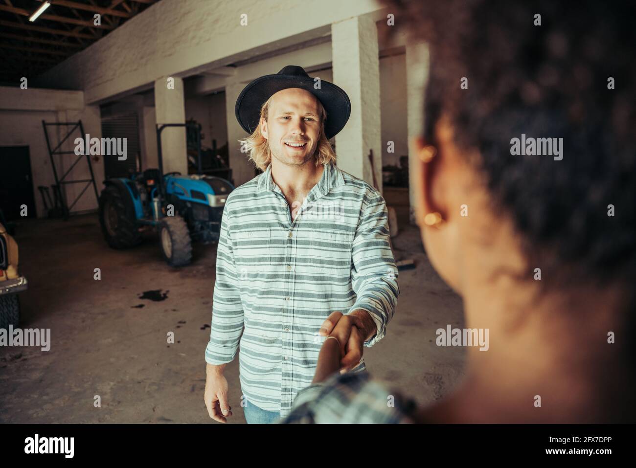 Caucasian male hand shake mixed race female colleague after day of work on farm Stock Photo