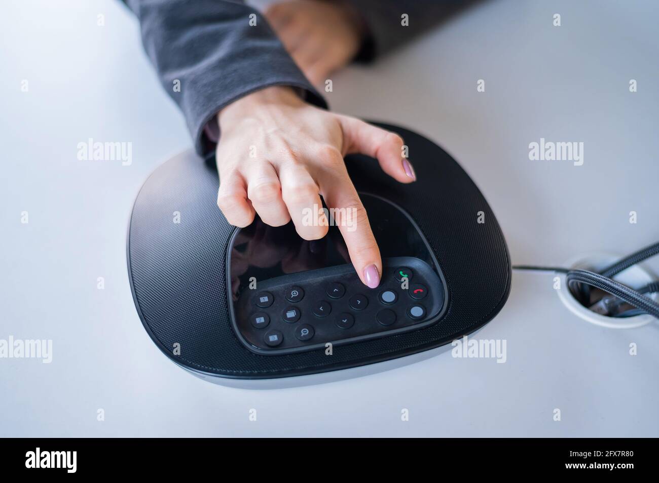 Hand on the speaker button. Business woman calling on the conference phone Stock Photo