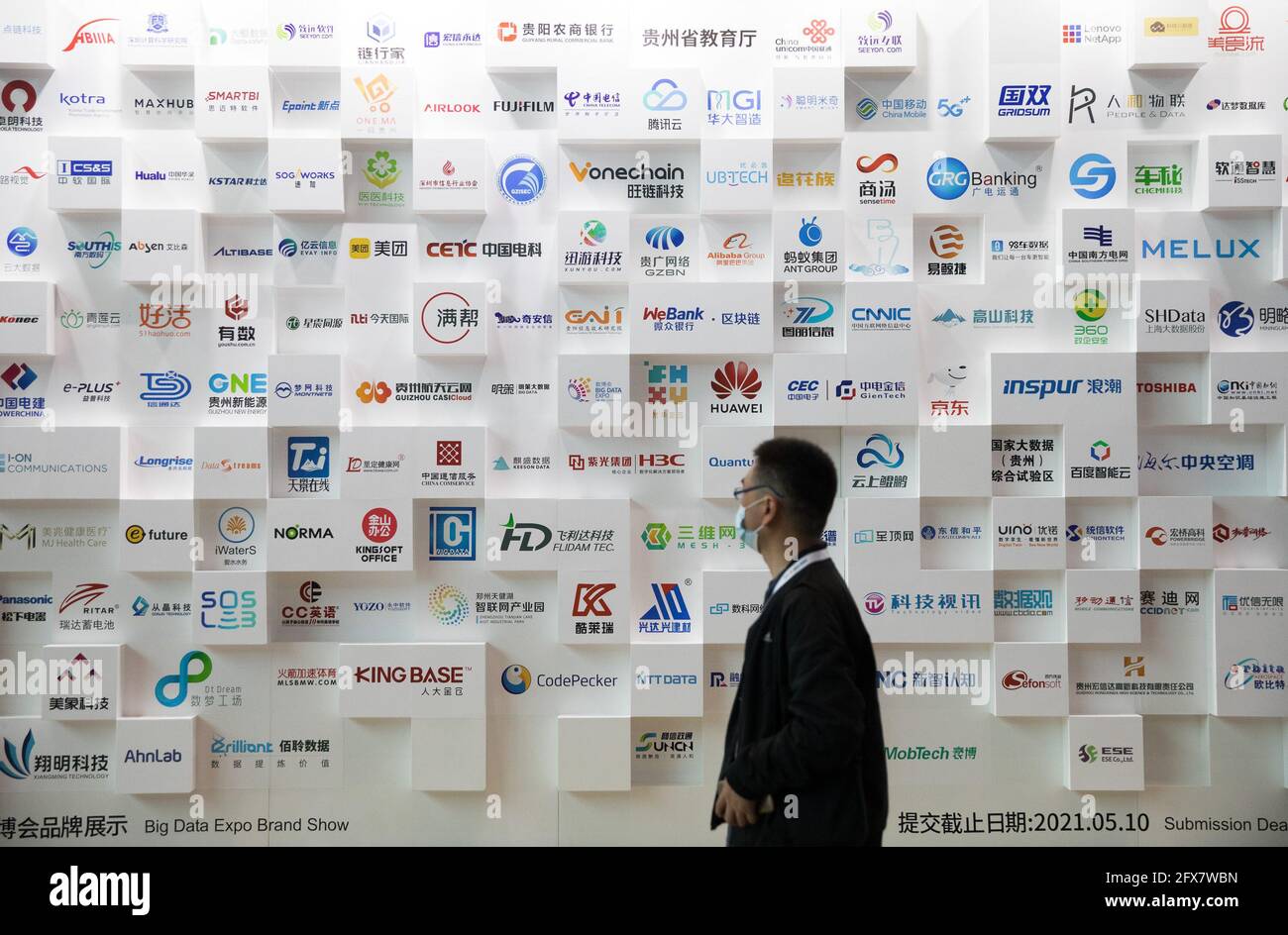 (210526) -- GUIYANG, May 26, 2021 (Xinhua) -- A visitor walks past a billboard displaying brands of exhibitors at the China International Big Data Industry Expo 2021 in Guiyang, southwest China's Guizhou Province, May 26, 2021. The China International Big Data Industry Expo 2021 opened here on Wednesday, showcasing cutting-edge scientific and technological innovations and achievements in the relevant area. Under the theme "Embrace digital intelligence, Deliver new development," this year's expo is scheduled both online and offline. The expo will witness six high-level dialogues to discuss Stock Photo
