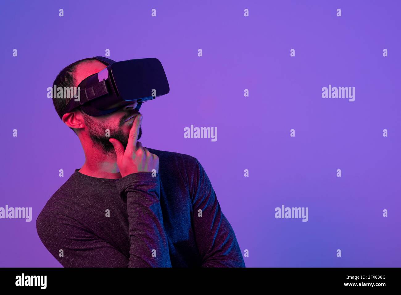 young man using virtual reality headset, experiencing immersion in virtual reality, concentrated while working Stock Photo
