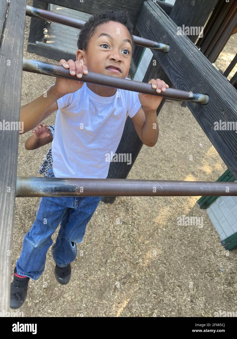 Vertical shot of a black American boy struggling to do pullups on monkey bars in a playground Stock Photo Alamy