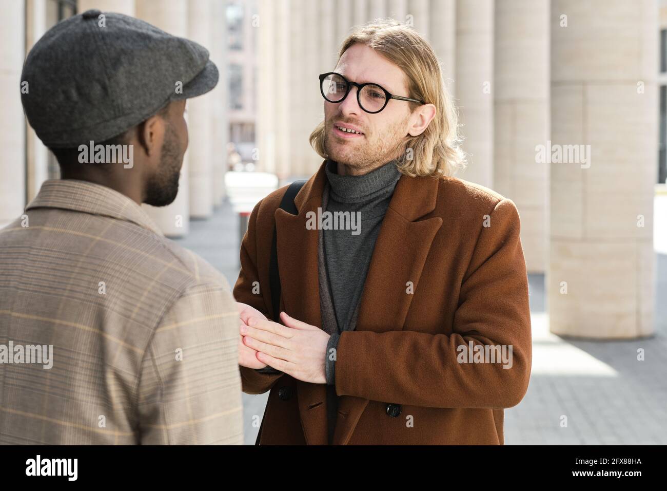 Two colleagues talking to each other while meeting on the street Stock Photo