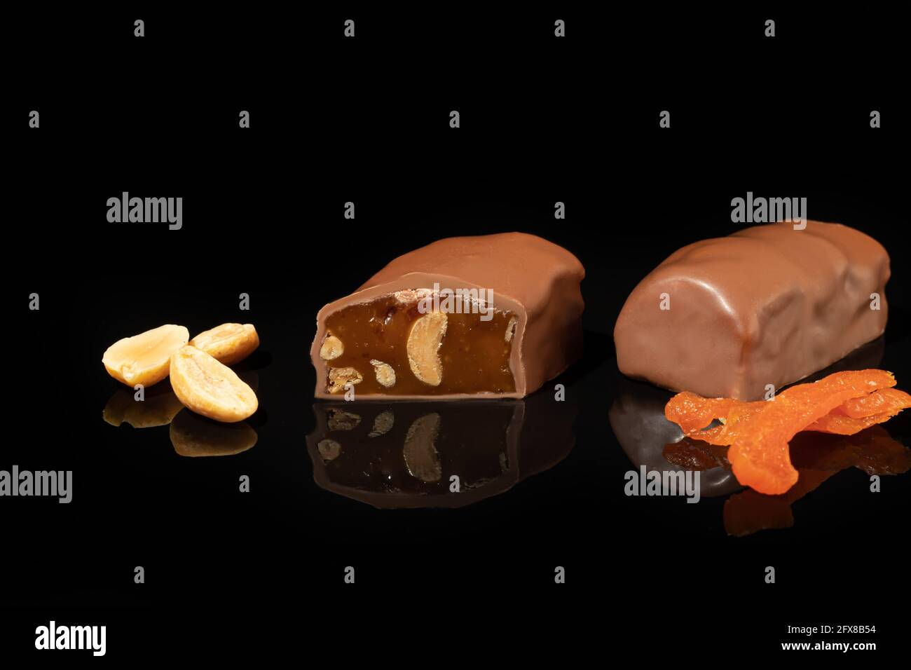 Chocolate candies on a dark background with reflection. Piece by piece and as a whole. Filling of nuts and fruits. Copy space. Stock Photo