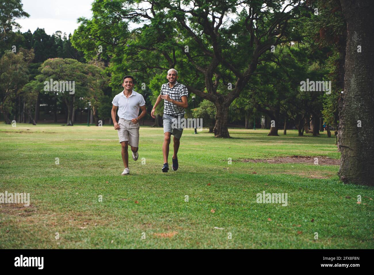 Young latin american gay couple running in a public park. Stock Photo